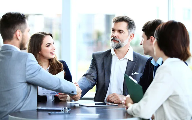 Executives shaking hands across a meeting table