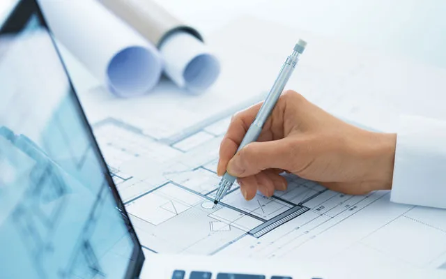 Hard hat and drawing tools over construction blueprints