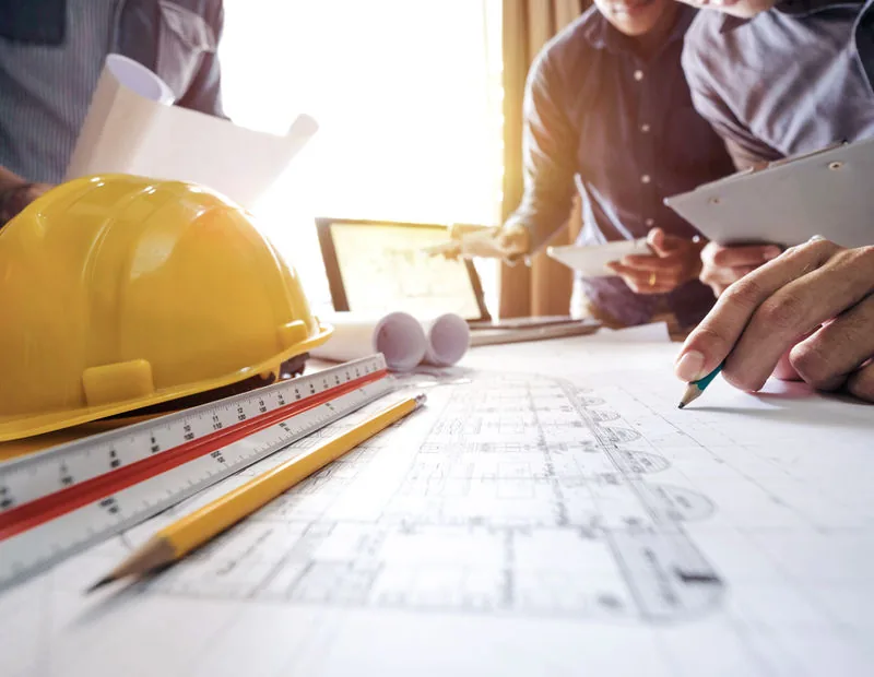 Hard hat and drawing tools over construction blueprints
