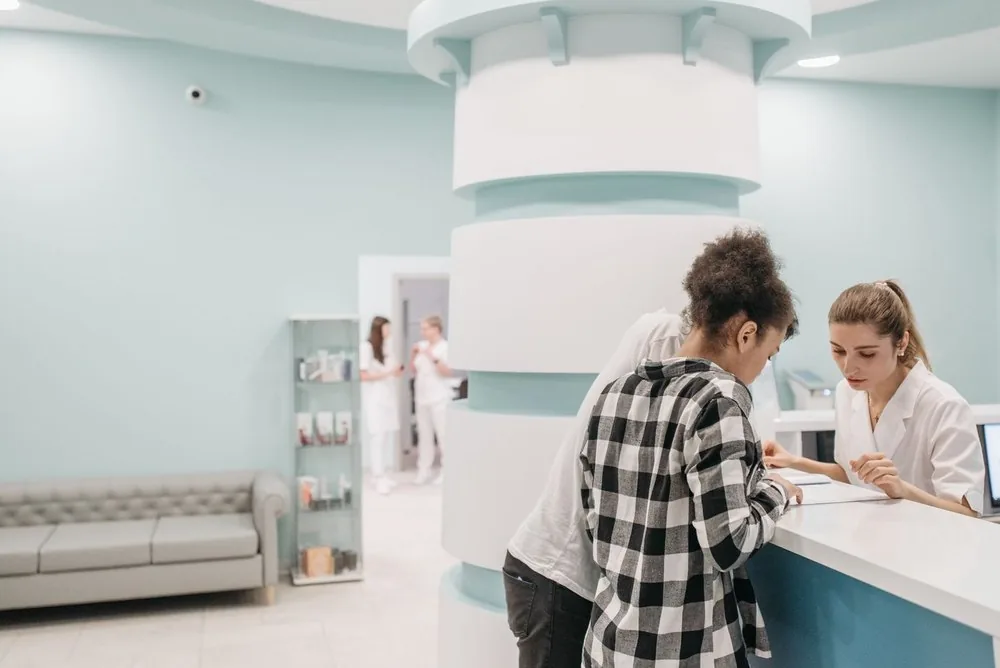 Clinic receptionist helping a patient at the front desk